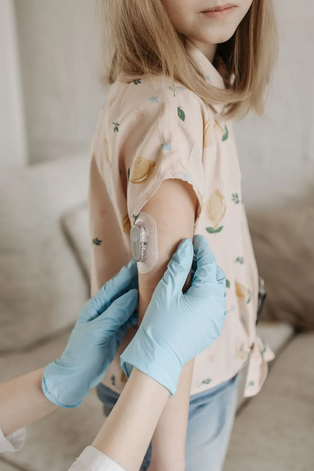 Una niña con un sensor de glucosa en el brazo, acompañada por una adulta.